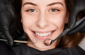 Paciente sorrindo em avaliação na Sculpere, clínica para colocar prótese dentária em Campinas, enquanto dentista segura espelho clínico.